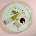Zdjęcie jedzenia przedstawiające kawałek sernika matcha z sosem wiśniowym na talerzu. fotografia kulinarna