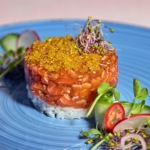 Zdjęcie jedzenia przedstawiające tatara z łososia na ryżu w formie krążka. fotografia kulinarna